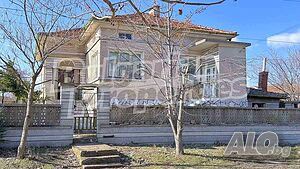 Къща с поддържан двор и камeнна ограда в центъра на хълмисто село
